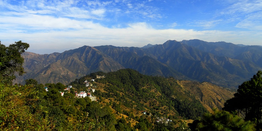 A scenic view of Lansdowne’s forested mountains with small clusters of buildings
