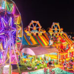 Illuminated Ferris wheel, bouncing castle and carousel in a funfair - Laos nightlife