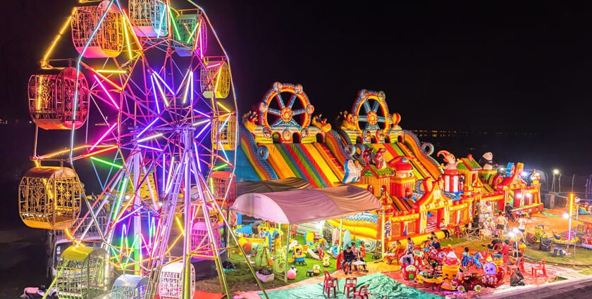 Illuminated Ferris wheel, bouncing castle and carousel in a funfair - Laos nightlife