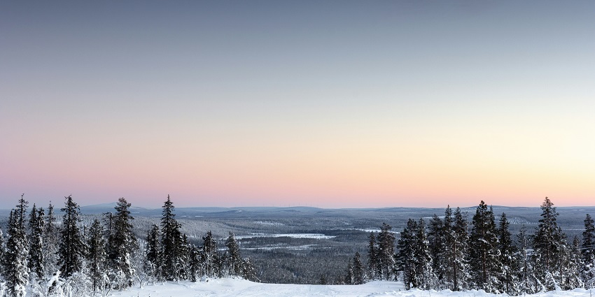 An image of Levi with snowy slopes, distant mountains, forested areas, and a clear sky.