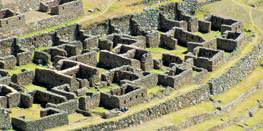 Stone ruins of Llactapata, a hidden Inca site near Machu Picchu, amid green valleys.