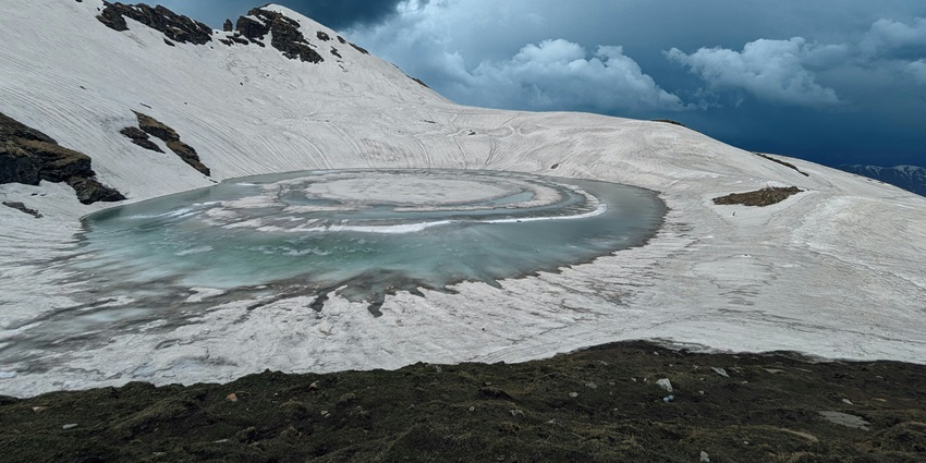 Breathtaking view of Bhrigu lake in Kullu surrounded by snow covered mountains.