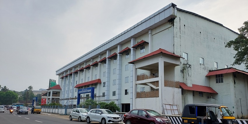 Kottayam indoor stadium building with vehicles parked on the sides on Kottayam Street.