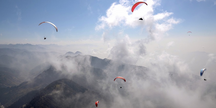 Paragliders fly amid clouds above Bir in Himachal Pradesh