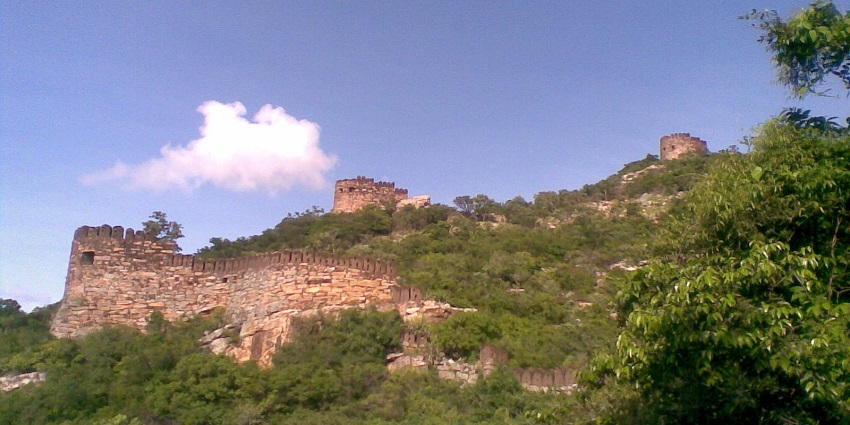 Stone walls and bastions of Udayagiri Fort standing atop a rocky hill with greenery around