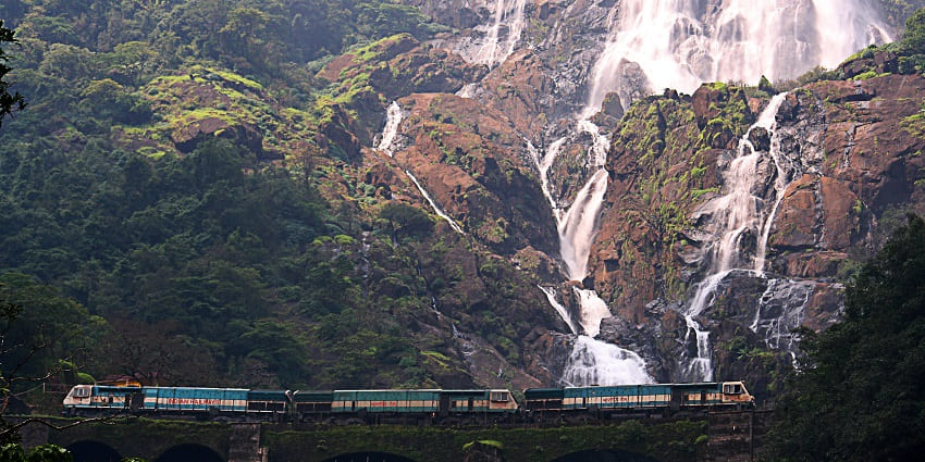 An Indian Railway locomotive passes through a bridge near the majestic Dudhsagar Waterfalls en route to Goa.