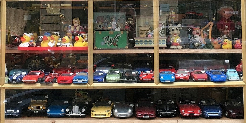 An image showing a shop window with a collection of toys, dolls, car models in Munich, Germany.