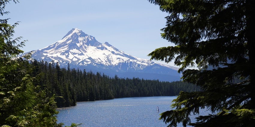 A lone windsurfer sails in the Lost Lake as a giant Mount Hood stands in the background.