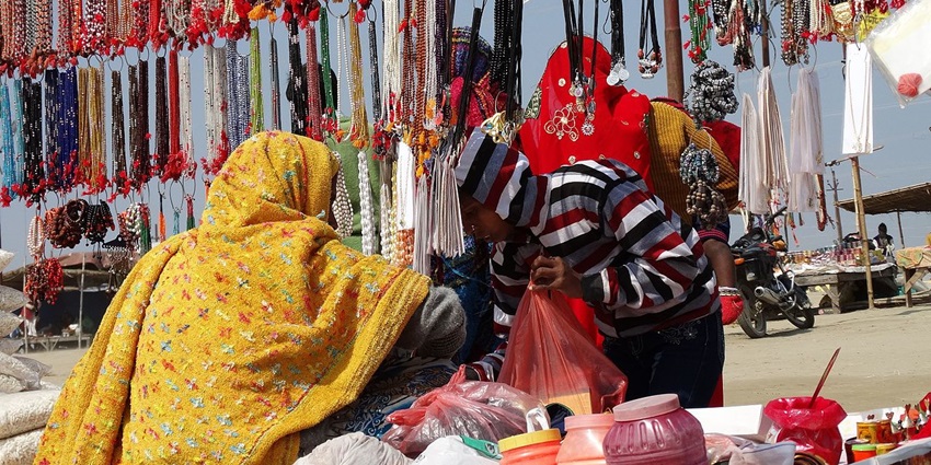 Crowd viewing tribal crafts at Aadi Mahotsav exhibition stall in open-air setting