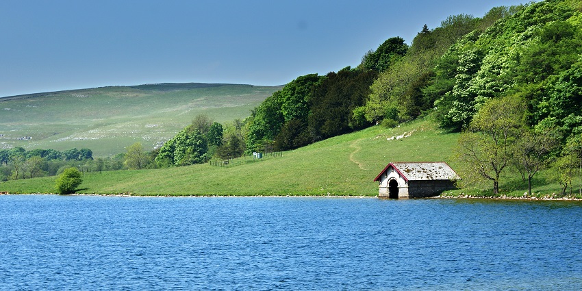 Boathouse on the north shore of Malham Tarn with blue waters and greenery around