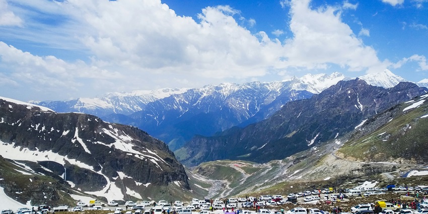 An image of a snowy landscape with trees in Manali, Himachal Pradesh, with people walking on a snow-covered path