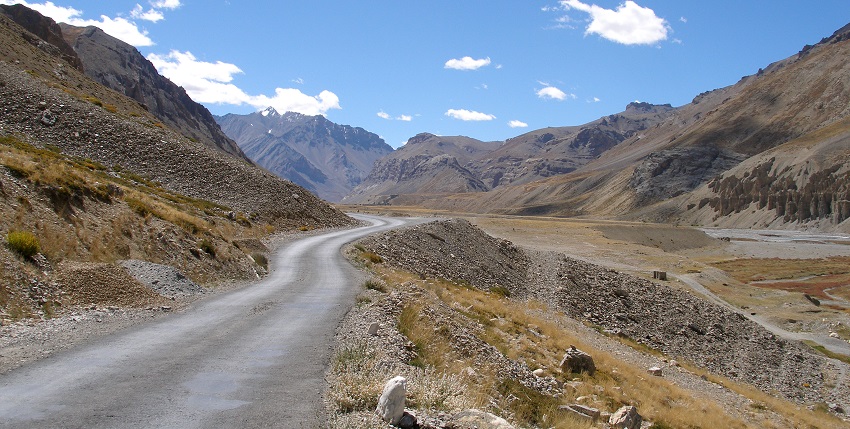 image of manali-leh highway cutting through a dry, mountainous valley under a blue sky