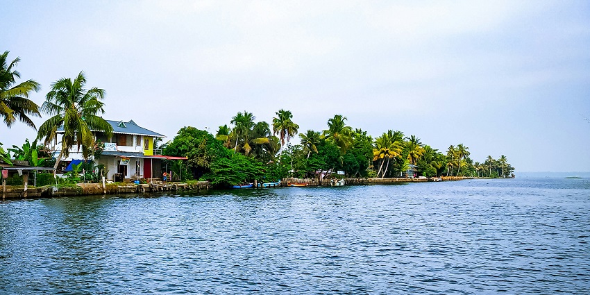 Sunrise view of the Mananchira Lake with buildings and greenery surrounding it.