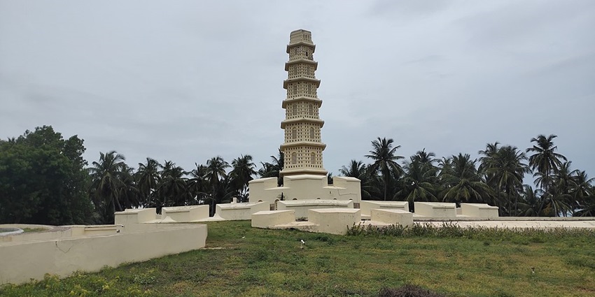 Manora Fort tower, India, with a tiered structure, surrounded by greenery and a cloudy sky
