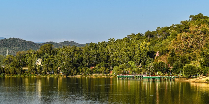 Mansar Lake with buildings and a temple hidden in the greenery - Famous Lakes In Jammu And Kashmir