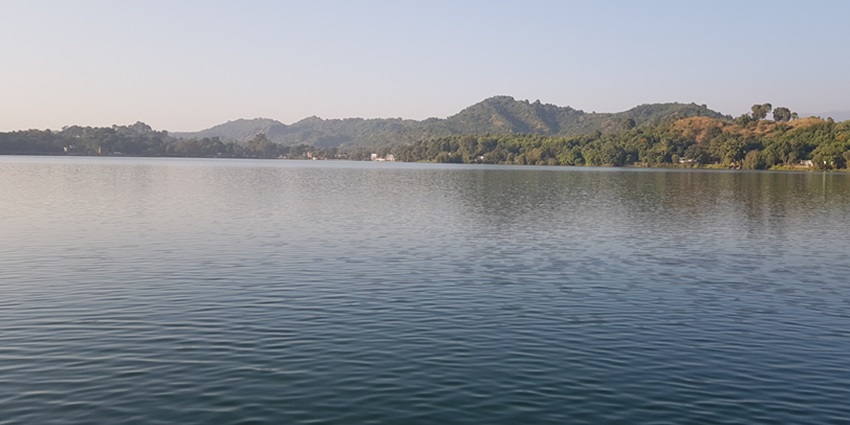 An image of Mansar Lake with tranquil waters, lush greenery, and a serene natural landscape