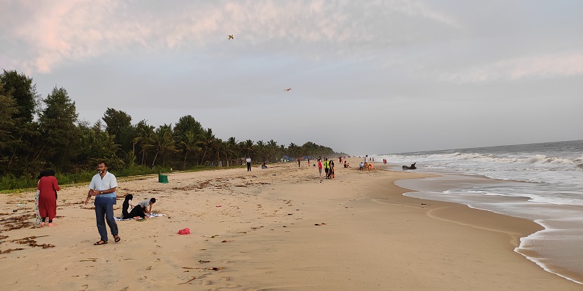 Marari Beach with sandy shoreline and people flying kites and enjoying at the beach.