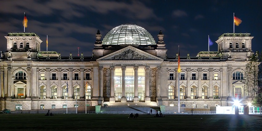 An image showing the Reichstag building illuminated at night, showcasing its grand architecture