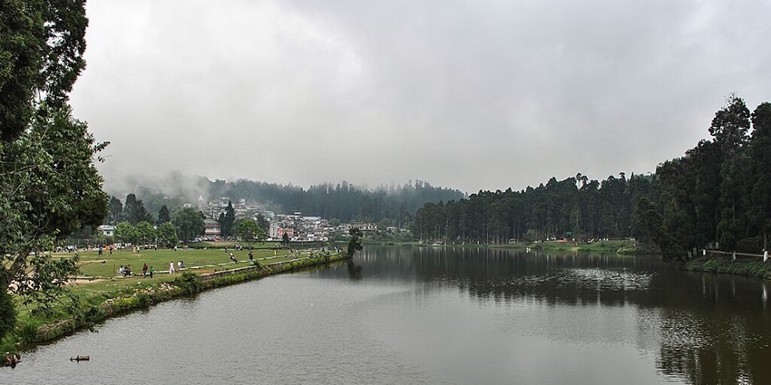 Sumendu Lake in West Bengal, with a green shoreline, and water surrounded by greenery.