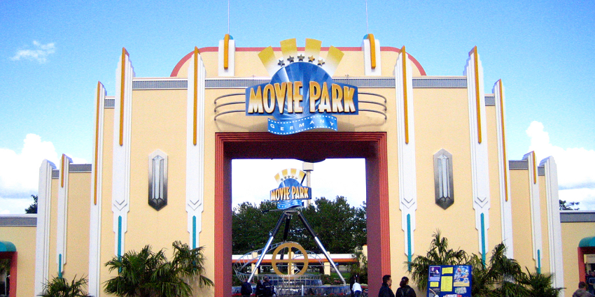 Image of an amusement park with ferris wheel and other rides along with the crowd