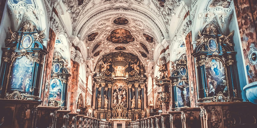 An image of an ornate church interior with detailed frescoes, intricate carvings, and grand altars during Christmas.