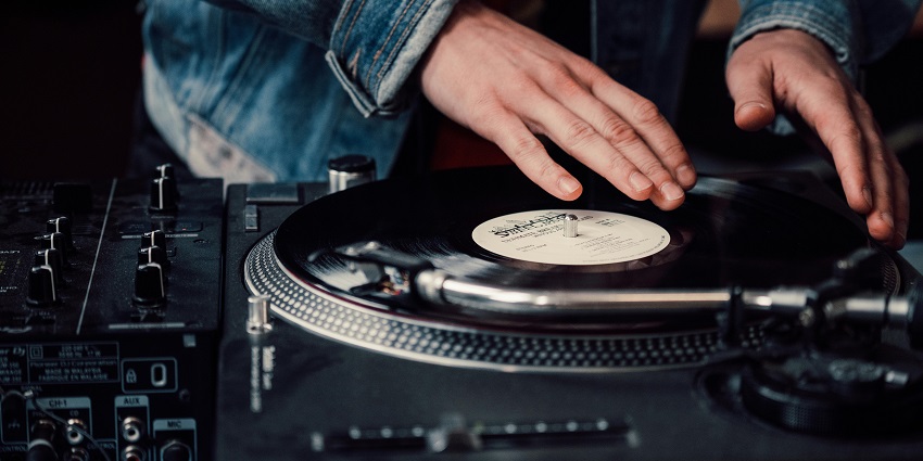 An image of a close-up view of a DJ operating a turntable in a Mumbai club.