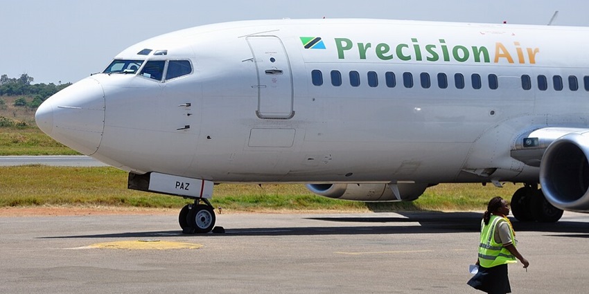 Precision Air aircraft parked on the runway of Mwanza airport with a maintenance staff walking by the side