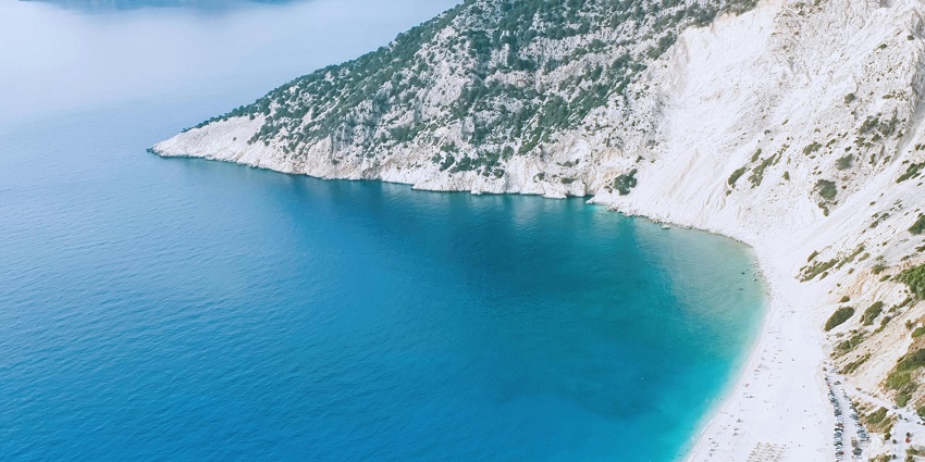 View from top of the hill of Myrtos beach with clear blue water and golden sand
