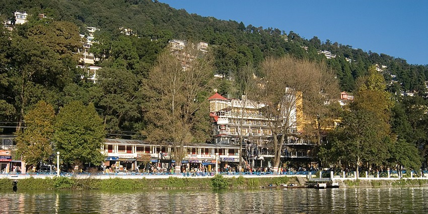 An image of Naini Lake in Nainital, surrounded by dense green hills with autumn reflections on the water.