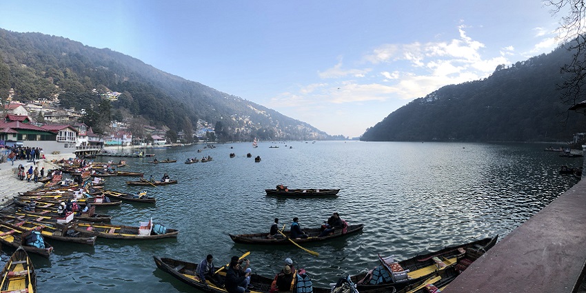 A picturesque view of Nainital Lake, one of the major lakes in India, surrounded by rolling hills and lush forests.