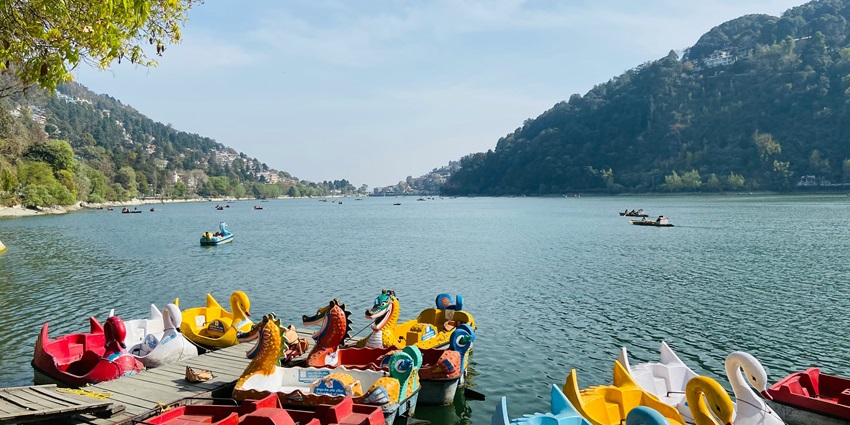 An image of a serene lake surrounded by green hills - places to visit in August in North India