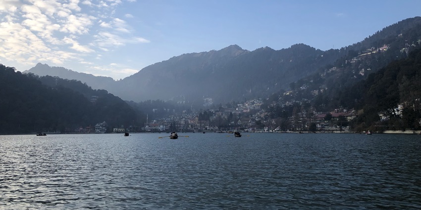 A majestic view of a tranquil lake in Nainital with views of lush hills in the background