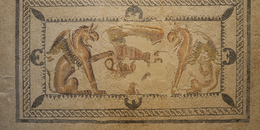 Ancient mosaic depicting two griffins facing each other, with a decorative border and faded details