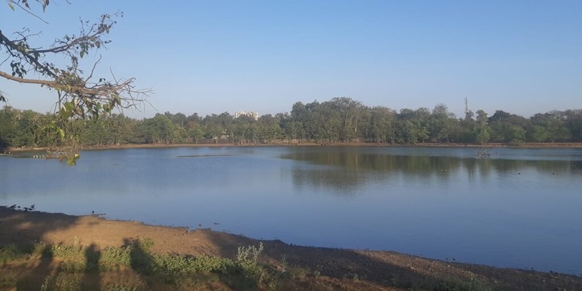 Lake inside the new palace in Kolhapur with sandy shoreline and trees in the back