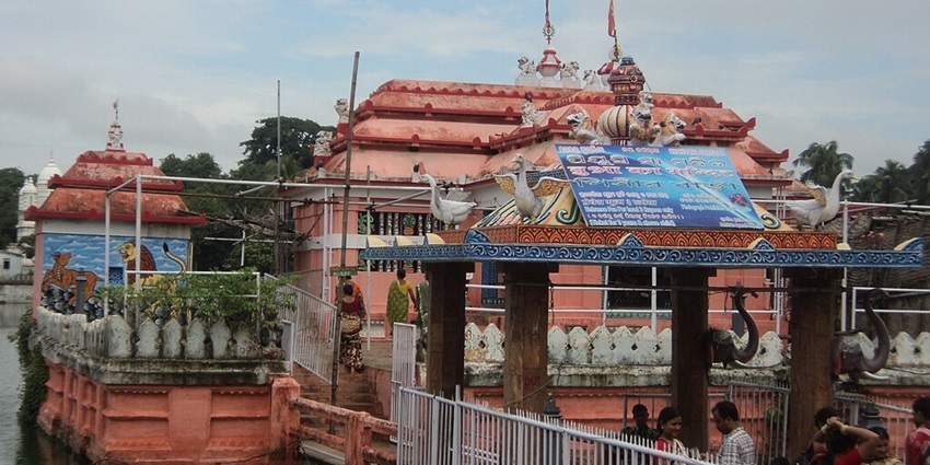 Temple beside a pond with detailed architecture and a signboard on the entrance