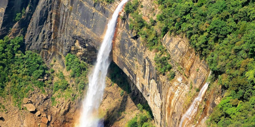An image showing Nohkalikai Falls in Meghalaya, India, with water flowing from a cliff.