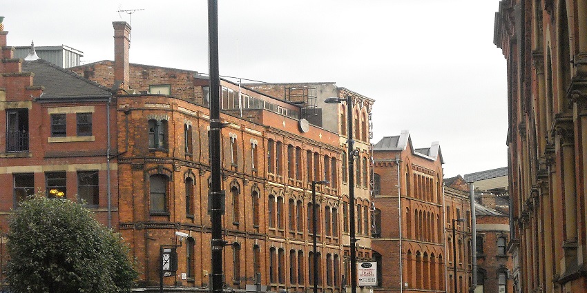 Northern Quarter in Manchester, with historic red-brick buildings, and moving vehicles.