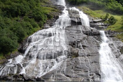 An image showing a majestic Norway waterfall cascading down lush green cliffs.