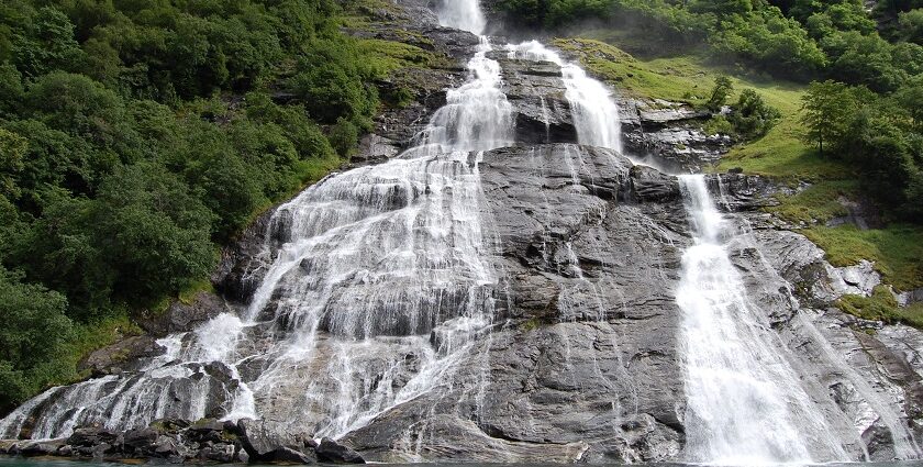 An image showing a majestic Norway waterfall cascading down lush green cliffs.