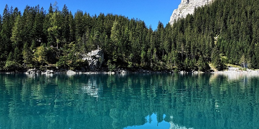 An image view of Lake Oeschinen in Switzerland with turquoise waters, alpine mountains, and greenery