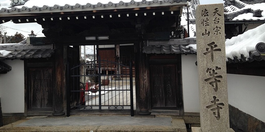 Byodoji temple entrance gate in the Omi-Hachiman old town with a sign on a stone pillar.