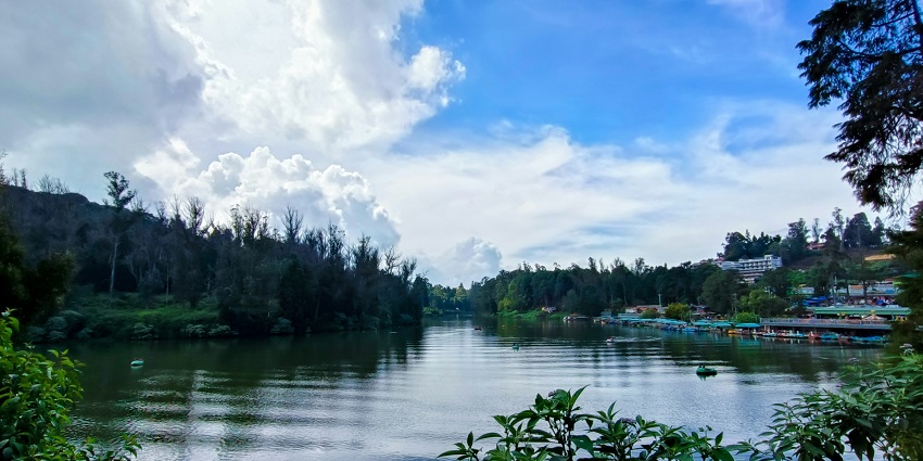 Tourists stand on the railings as paddle boats stand parked on the Ooty Lake.