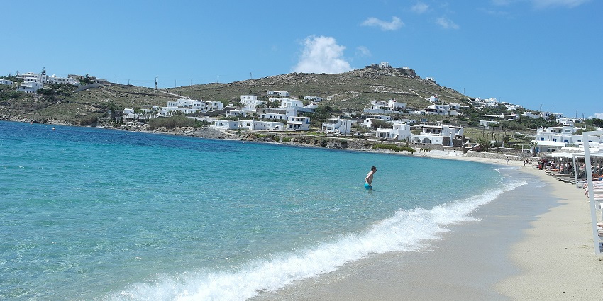 Image of Ornos seashore with golden sand and clear blue water under blue sky