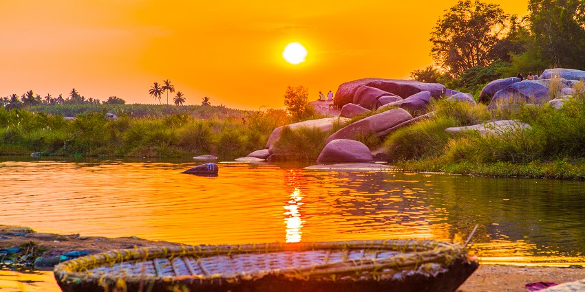 Sunset on river surrounded by lush green forest and scenic landscape of Hampi
