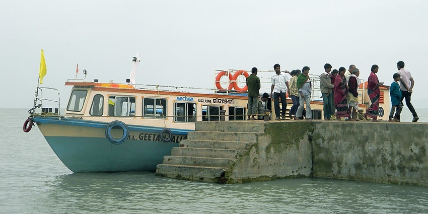 Chilika Lake with people standing on the platform and a boat parked next to its stairs