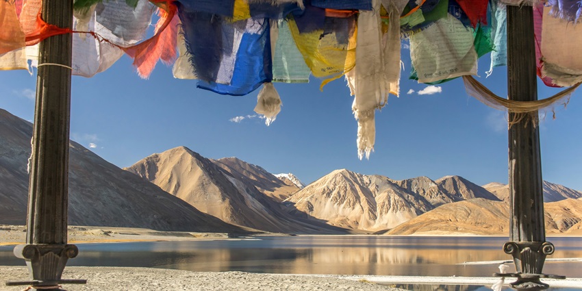 Image Tibetan buddhism flags hanging near a lake and mountains during day time