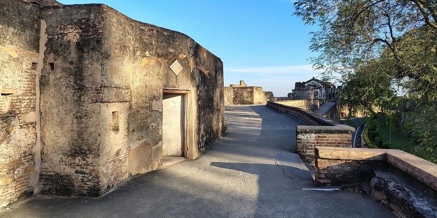 Ancient fort walls standing tall under a vibrant blue sky with scattered clouds