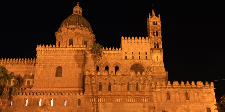 Palermo Cathedral at night, showing its illuminated facade and architectural details.