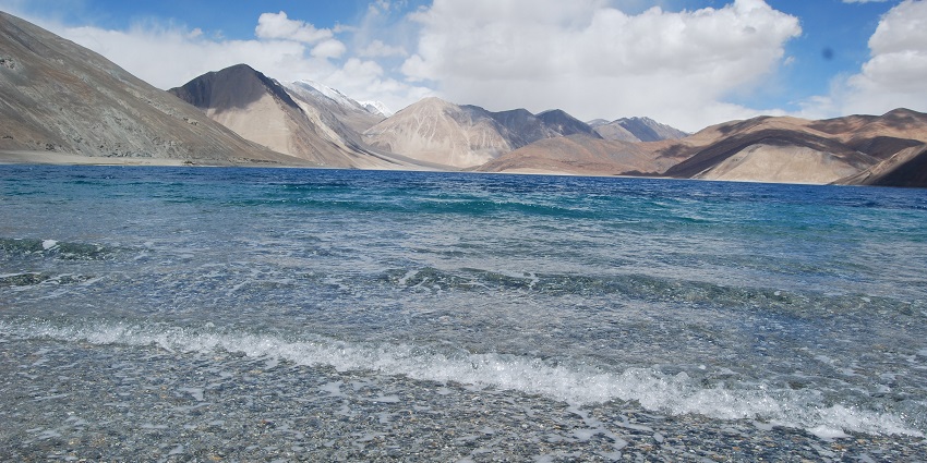 An awe-inspiring view of Pangong Lake, with its shimmering blue waters contrasting against the rugged mountains of Ladakh.