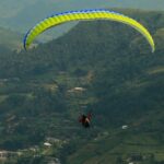 A tourist paragliding in Leh amidst the hills, valleys and green terrains of this lush landscape